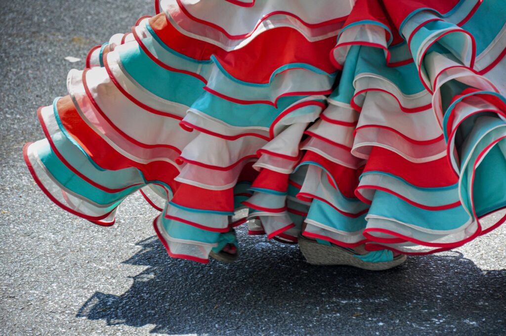 Detalle de los volantes rojos, blancos y turquesas de un vestido de baile.