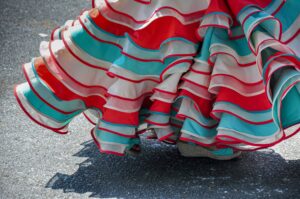 Detalle de los volantes rojos, blancos y turquesas de un vestido de baile.