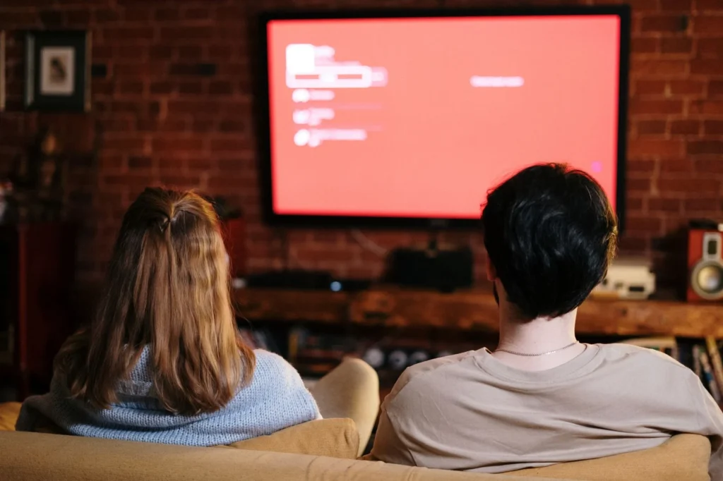 Dos personas viendo una pantalla de televisión