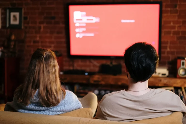 Dos personas viendo una pantalla de televisión